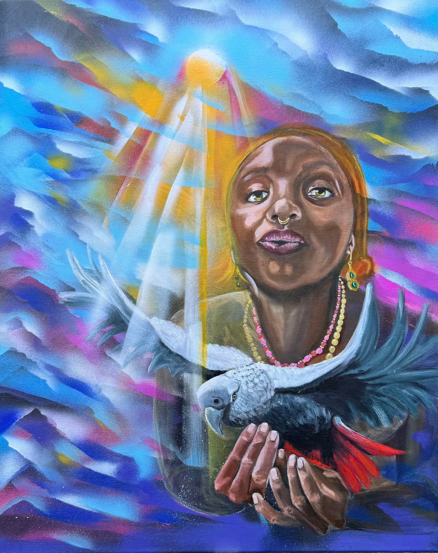 This piece portrays a suspended moment where a contemplative Oya lifts a striking African parrot into shafts of warm light amid a swirl of blues, magentas and gold. The subject’s steady gaze, septum ring and layered beads sit behind the bird’s slate plumage and red tail, creating a charged, intimate dialogue between spirit and wild. Luminous rays carve the haze, revealing soft hands, alert eyes and a tension that is at once tender and ominous—mystery tempered by quiet strength.