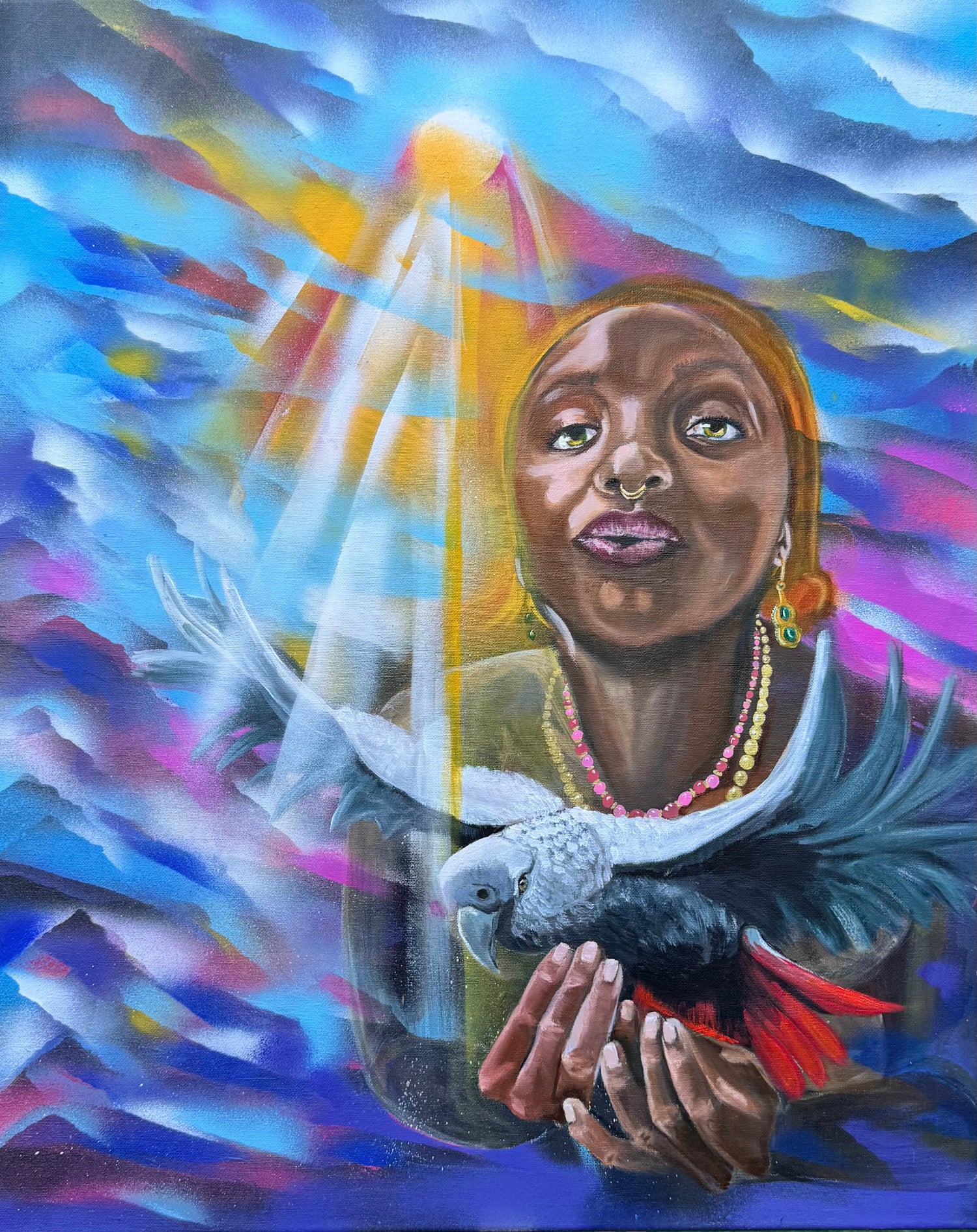 This piece portrays a suspended moment where a contemplative Oya lifts a striking African parrot into shafts of warm light amid a swirl of blues, magentas and gold. The subject’s steady gaze, septum ring and layered beads sit behind the bird’s slate plumage and red tail, creating a charged, intimate dialogue between spirit and wild. Luminous rays carve the haze, revealing soft hands, alert eyes and a tension that is at once tender and ominous—mystery tempered by quiet strength.